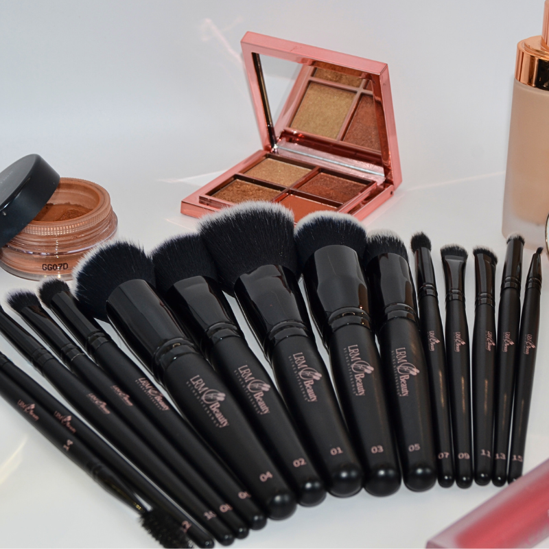 Set of makeup brushes with a compact powder and blush on a white background