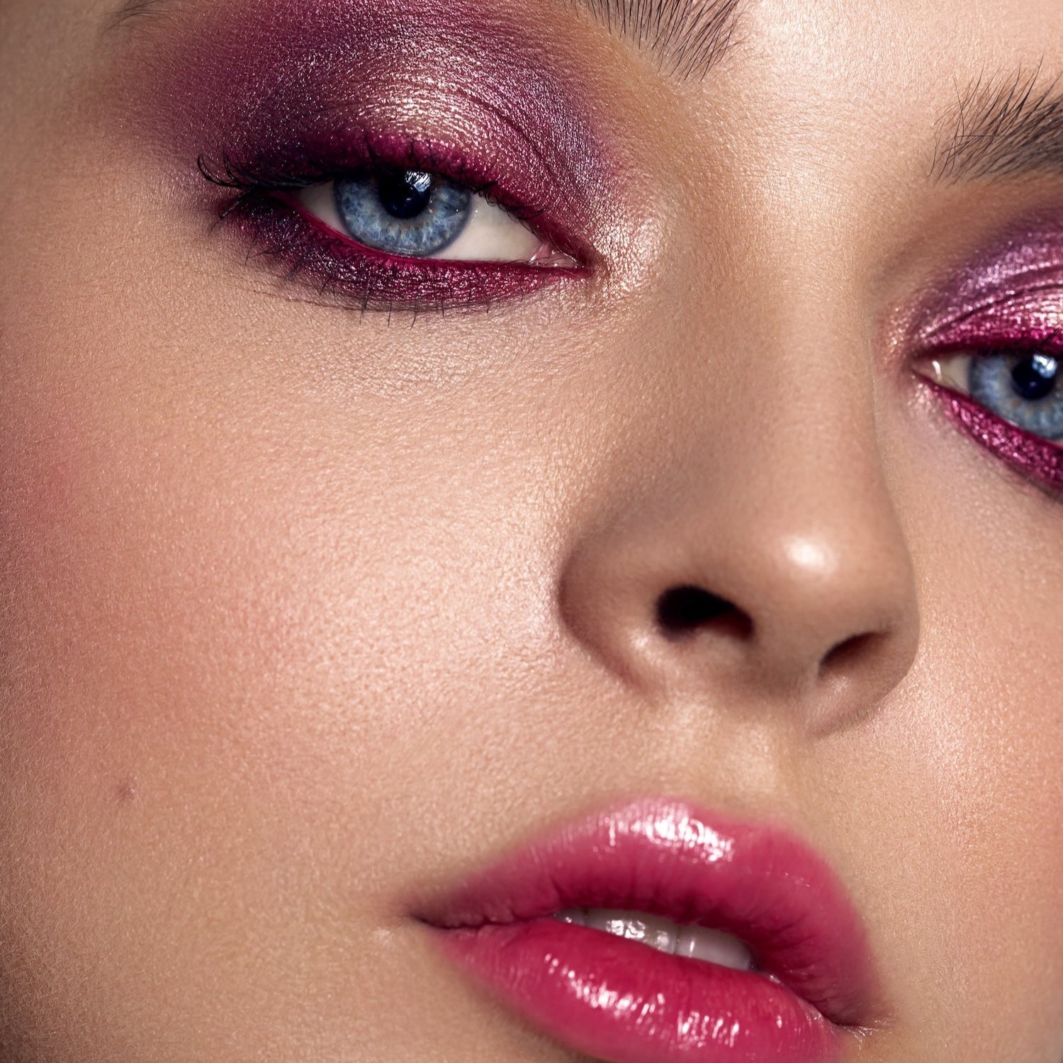 Close-up of a woman's face with pink and purple eye makeup